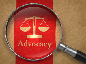 Advocacy Concept Magnifying Glass with Word Advocacy and Icon of Scales in Balance on Old Paper with Red Vertical Line Background.