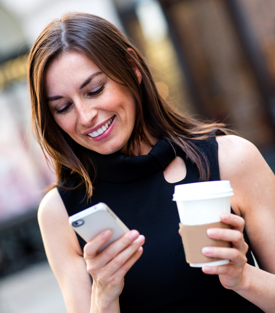 lady holding her iPhone in one hand, coffee in the other