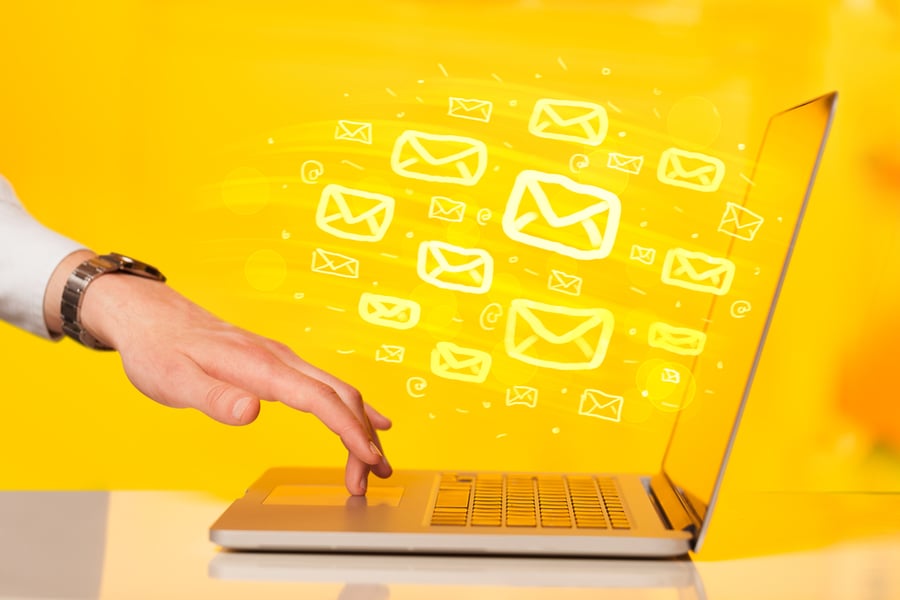 hand touching a laptop keyboard with one finger - yellow background