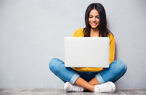 woman sitting on the ground holding her laptop on her lap