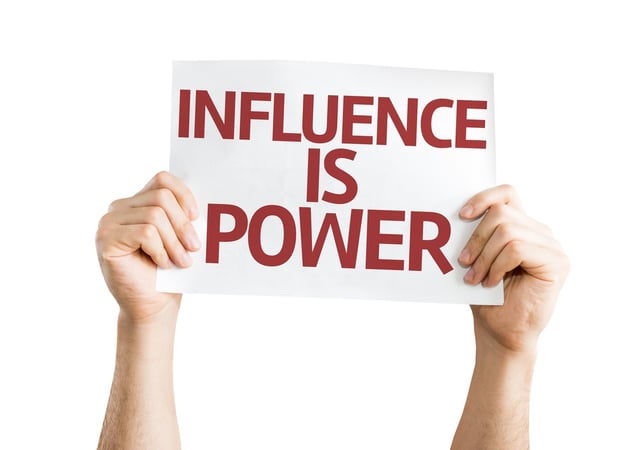 1. man with blue shirt and tie surrounded by people holding microphones 2. person holding a white poster with red words "Influence is Power"