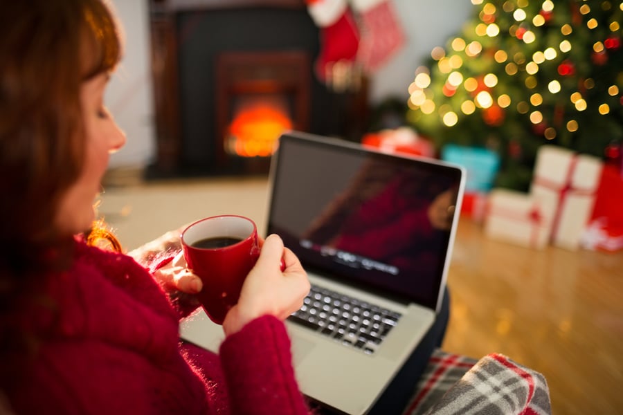 person holding a cup of coffee using their laptop