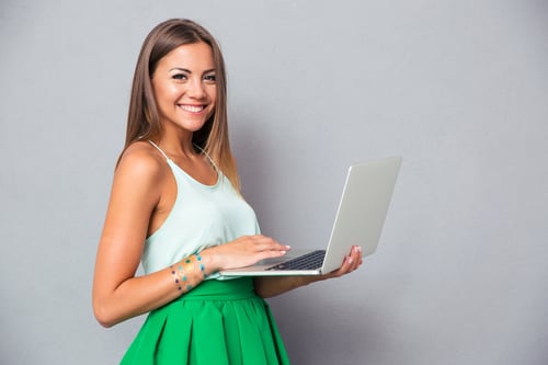 1. lady holding a laptop against a gray wall 2. hand holding a silver pen writing on white paper