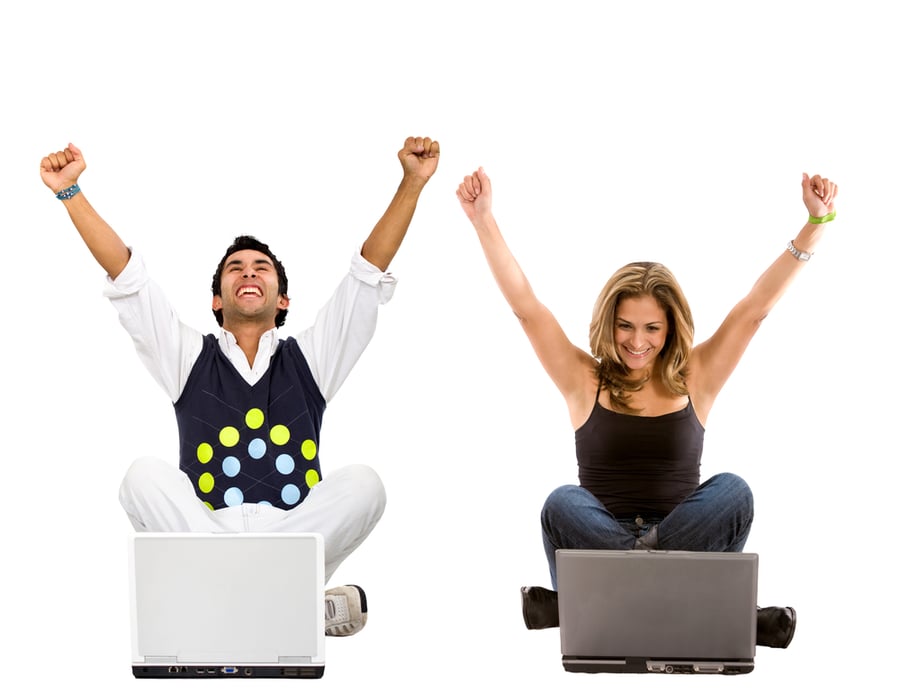 Man and Woman sitting behind their laptops with arms in the air