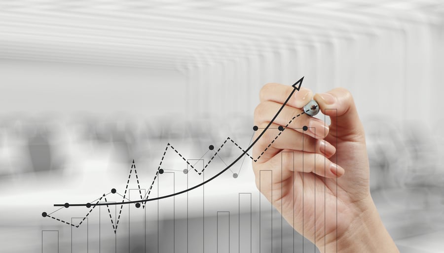 line graph drawn with a black marker held by a woman's hand on clear glass