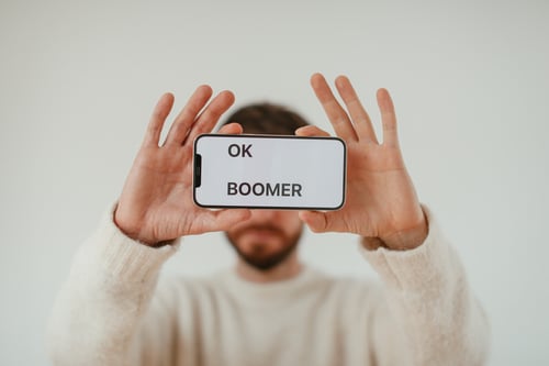 Man holding smart phone that says OK BOOMER
