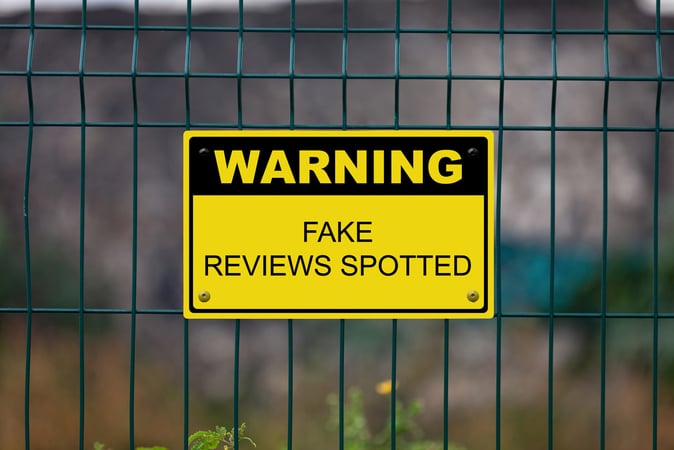 Sign on fence that says "Warning Fake Reviews Spotted